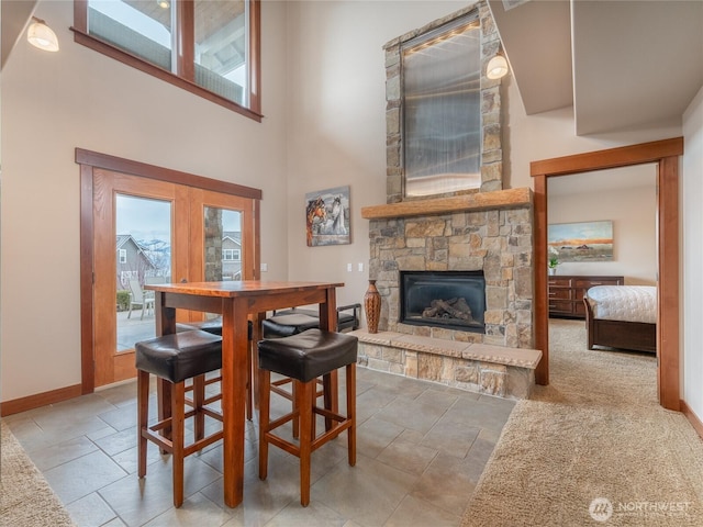 dining area with baseboards, a high ceiling, and a fireplace