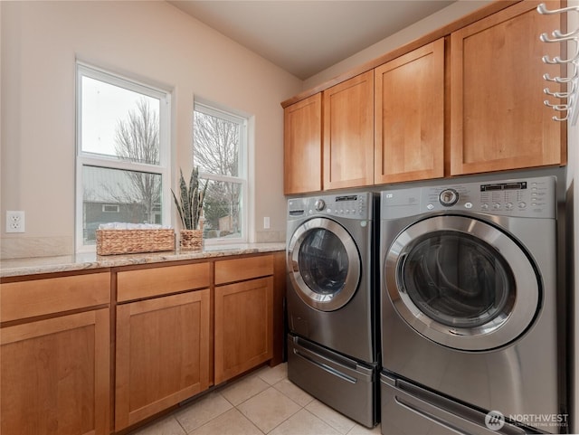 clothes washing area with light tile patterned floors, cabinet space, and separate washer and dryer