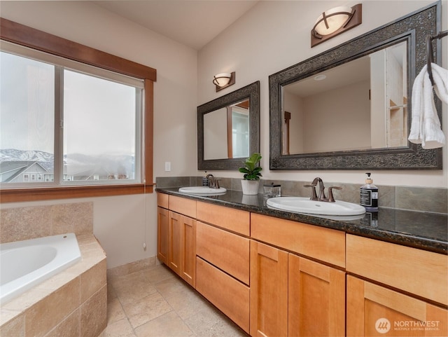 full bath with double vanity, baseboards, a garden tub, and a sink