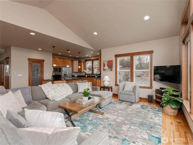 living area with recessed lighting, light wood-type flooring, baseboards, and vaulted ceiling