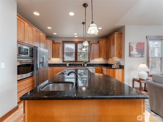 kitchen featuring a sink, an island with sink, light wood finished floors, and stainless steel appliances