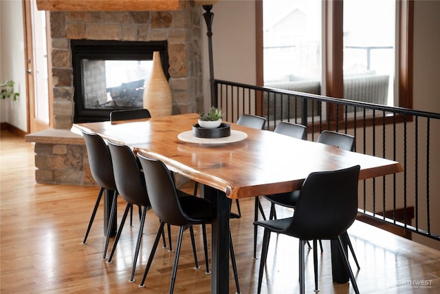 dining area featuring a stone fireplace and light wood-type flooring