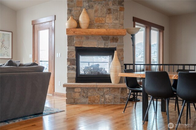 dining space with a stone fireplace, wood finished floors, and baseboards