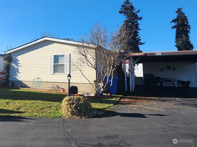 view of side of home featuring a yard and a carport