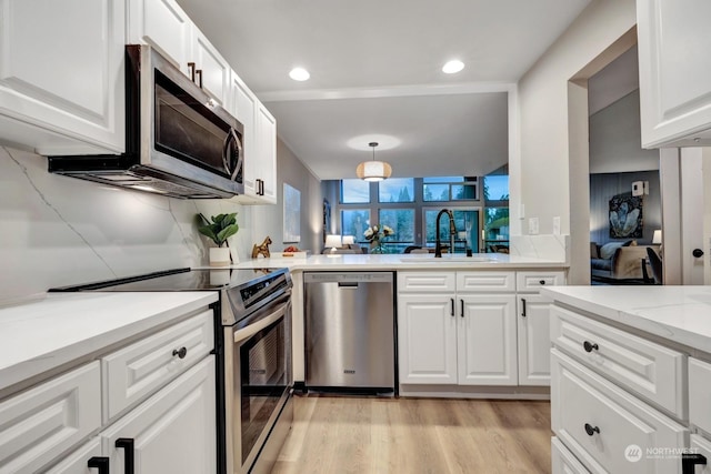 kitchen featuring sink, hanging light fixtures, white cabinets, and stainless steel appliances