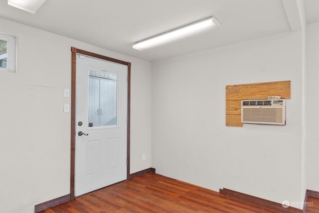 entrance foyer featuring a wall unit AC and dark wood-type flooring