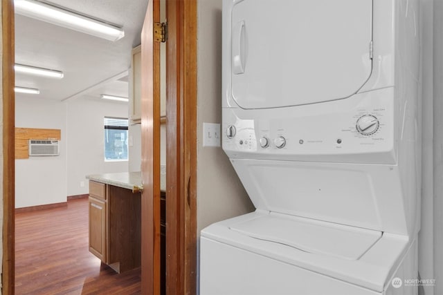 washroom featuring wood-type flooring, stacked washer and dryer, and a wall mounted air conditioner