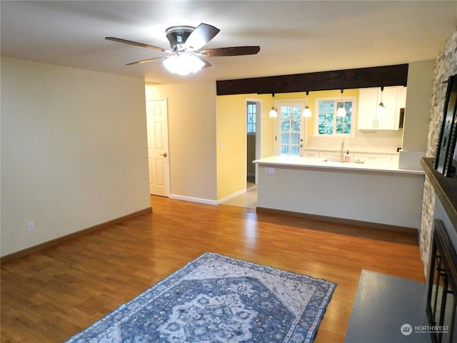 living room featuring a fireplace, ceiling fan, light hardwood / wood-style flooring, and sink