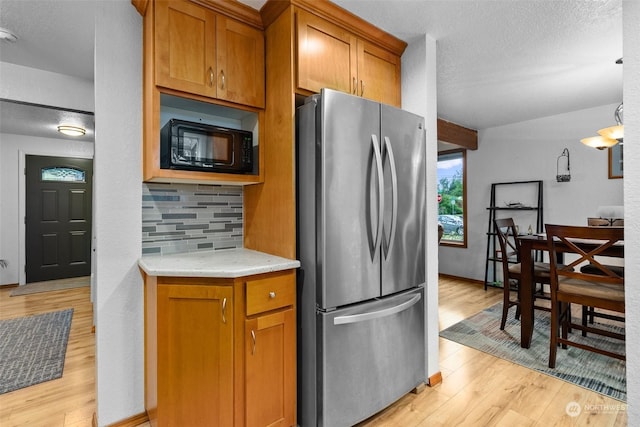 kitchen featuring tasteful backsplash, stainless steel fridge, light stone counters, and light hardwood / wood-style flooring