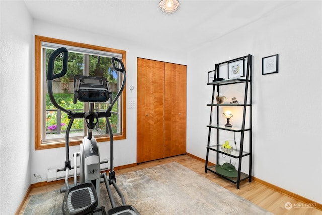 exercise area featuring wood-type flooring and a baseboard heating unit