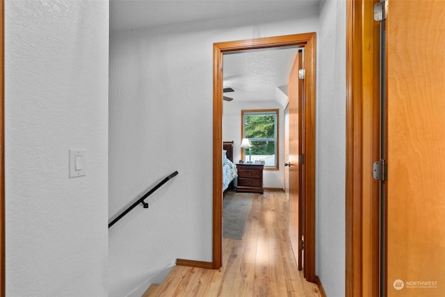 hall featuring a textured ceiling and light hardwood / wood-style flooring