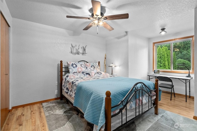 bedroom featuring ceiling fan, wood-type flooring, a closet, and a textured ceiling