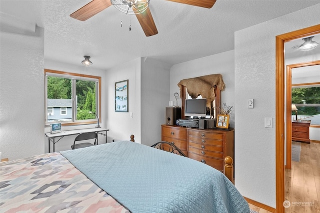 bedroom with ceiling fan, a textured ceiling, and hardwood / wood-style floors