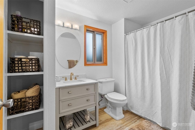 bathroom with toilet, vanity, wood-type flooring, and a textured ceiling