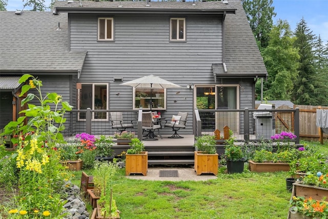 rear view of property featuring a deck and a yard