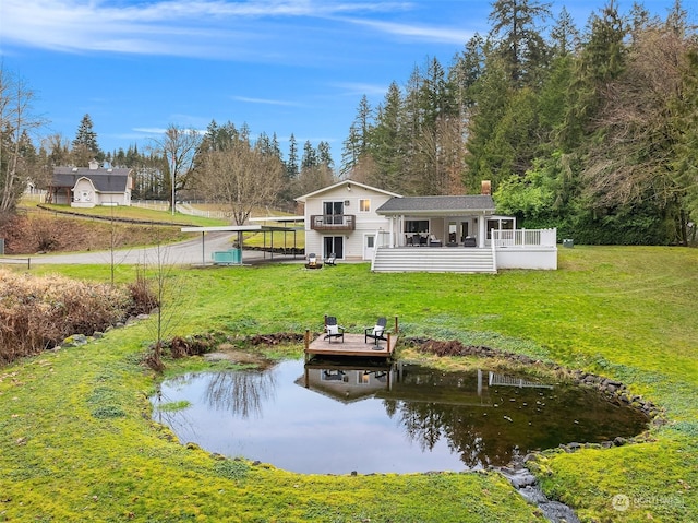 back of house featuring a water view and a lawn