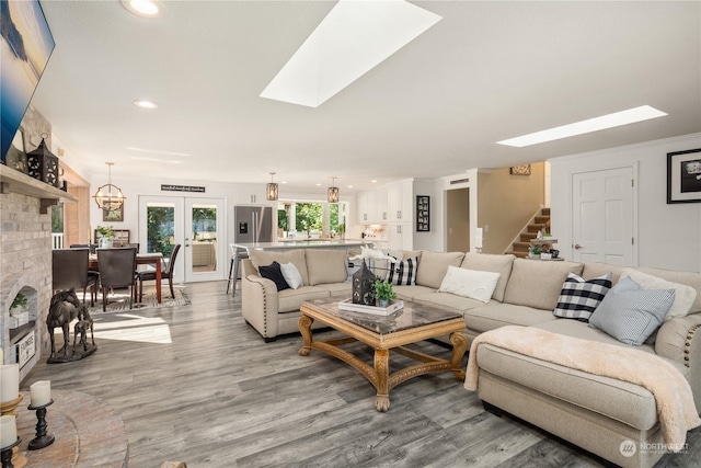 living room with light hardwood / wood-style flooring, a skylight, and french doors