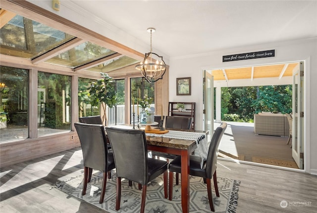 dining area with hardwood / wood-style flooring, ornamental molding, a notable chandelier, and a healthy amount of sunlight