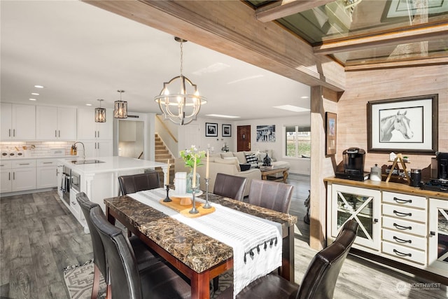 dining room with sink, hardwood / wood-style floors, beam ceiling, and a chandelier