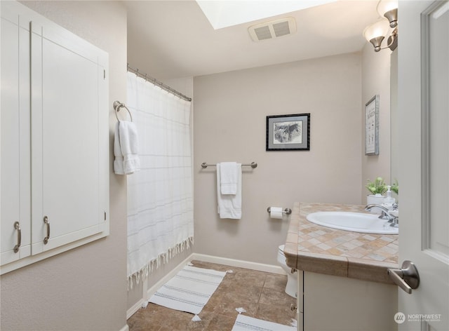 full bathroom featuring toilet, vanity, a skylight, and shower / bath combo