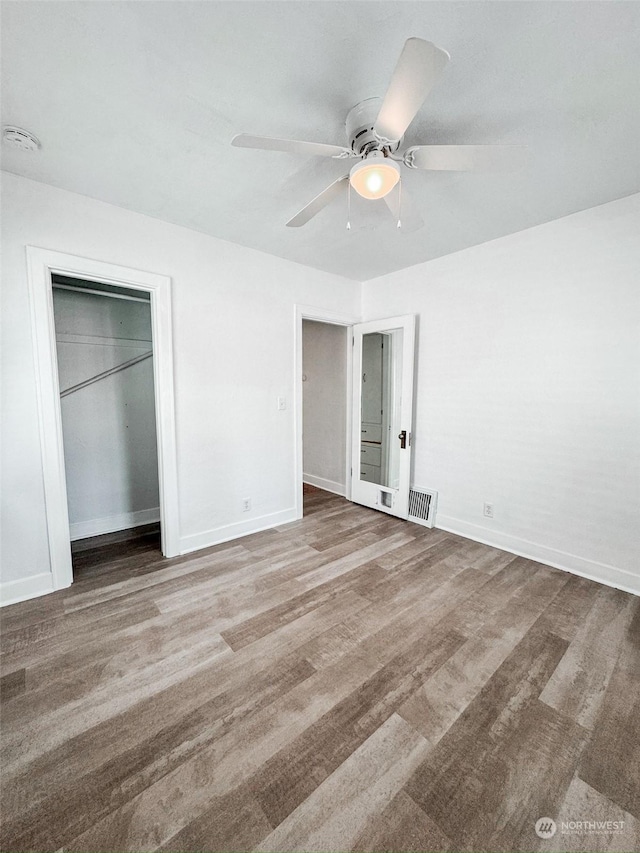 unfurnished bedroom featuring hardwood / wood-style floors, a closet, and ceiling fan