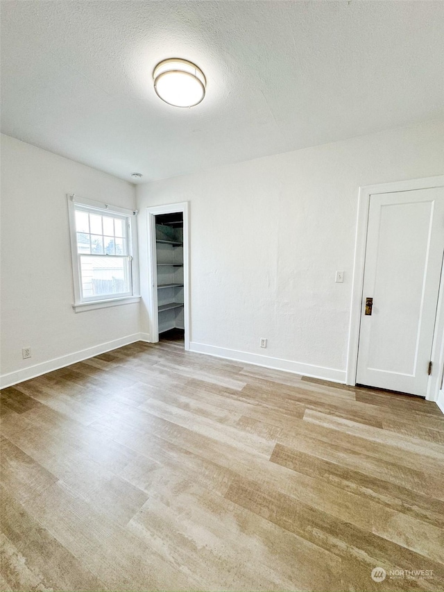 unfurnished room with a textured ceiling and light wood-type flooring