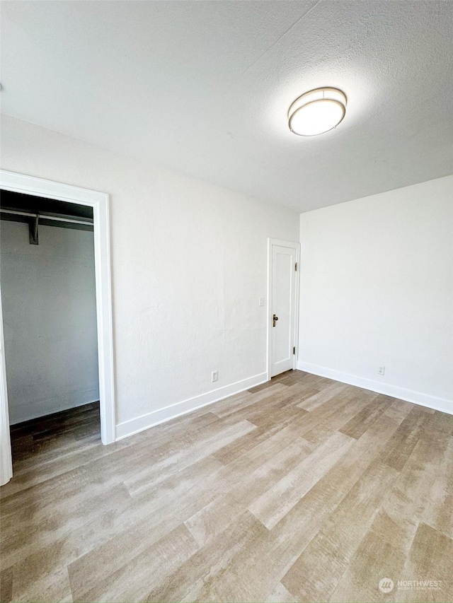 spare room featuring a textured ceiling and light hardwood / wood-style flooring