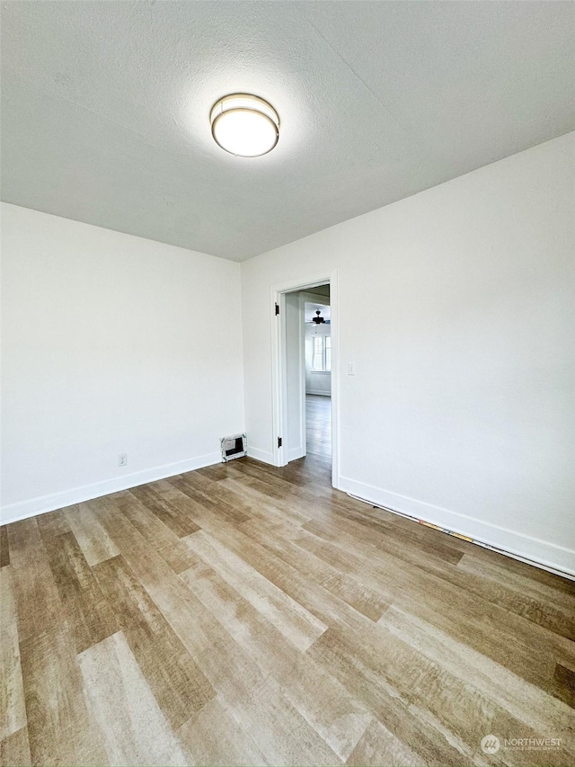 spare room featuring light hardwood / wood-style floors and a textured ceiling