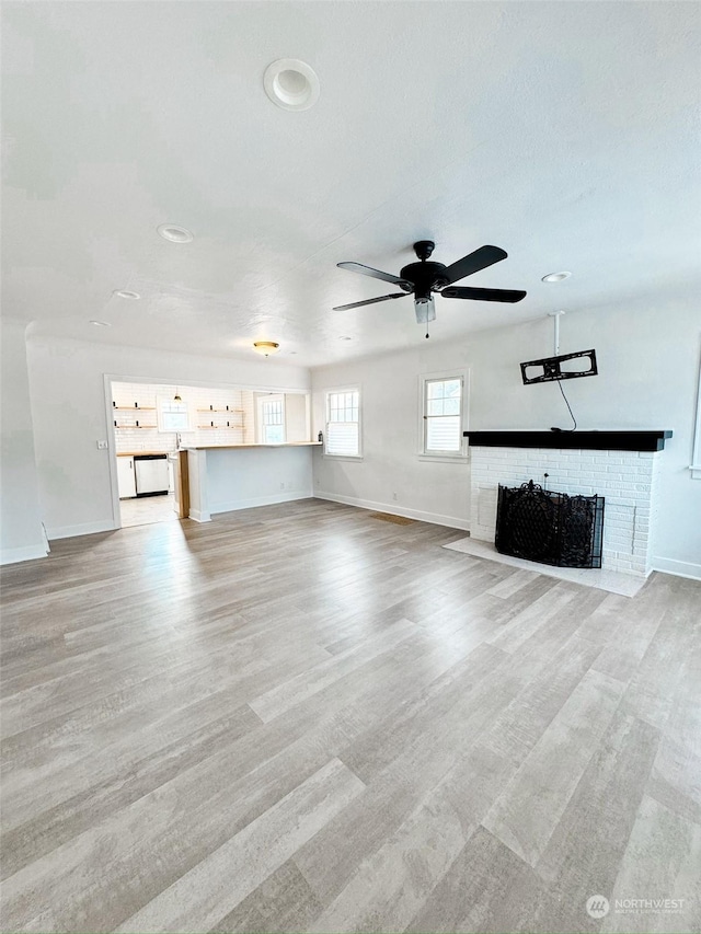 unfurnished living room featuring ceiling fan, a fireplace, and light hardwood / wood-style floors