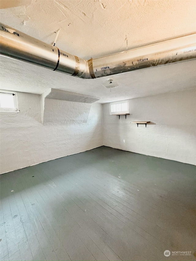 basement featuring wood-type flooring and a textured ceiling