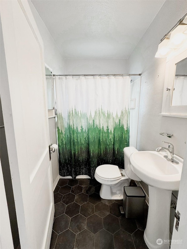 bathroom with toilet, a shower with shower curtain, and a textured ceiling