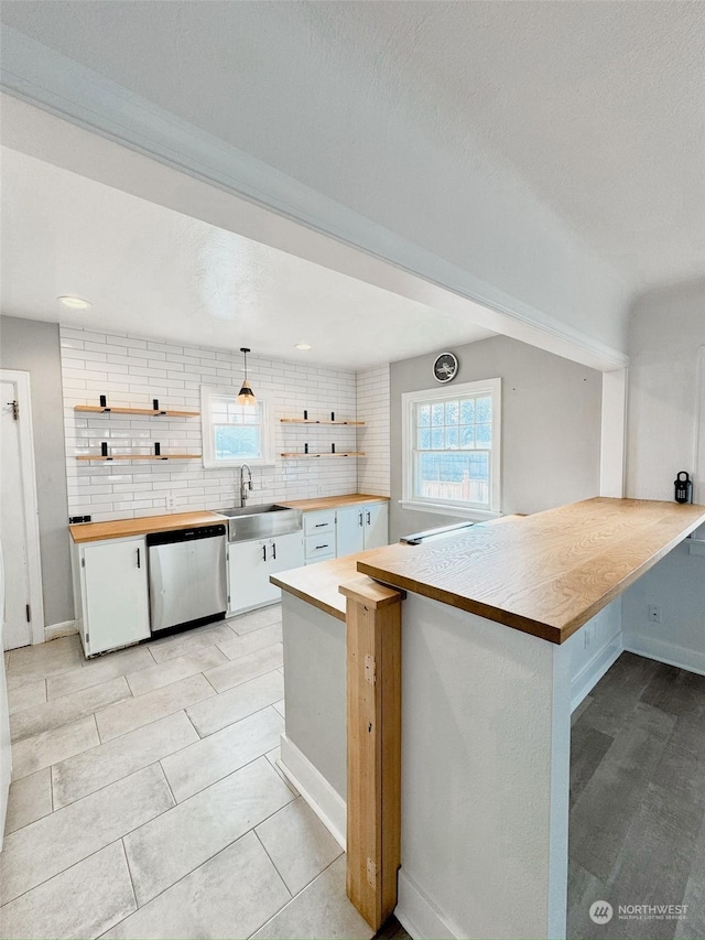 kitchen with decorative backsplash, stainless steel dishwasher, kitchen peninsula, and white cabinets