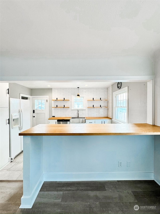 kitchen with sink, decorative backsplash, white fridge with ice dispenser, stainless steel dishwasher, and kitchen peninsula