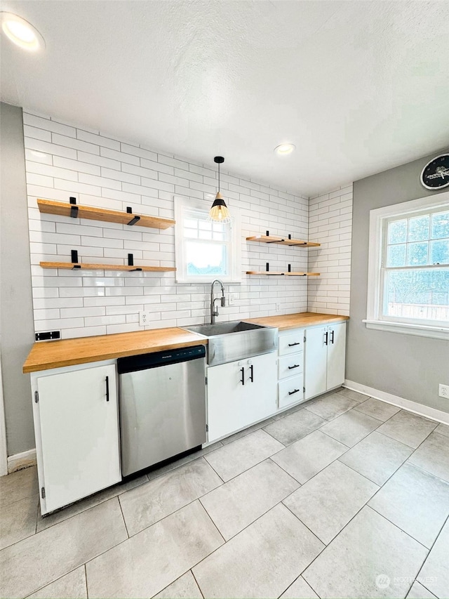 kitchen with sink, butcher block countertops, decorative light fixtures, dishwasher, and white cabinets