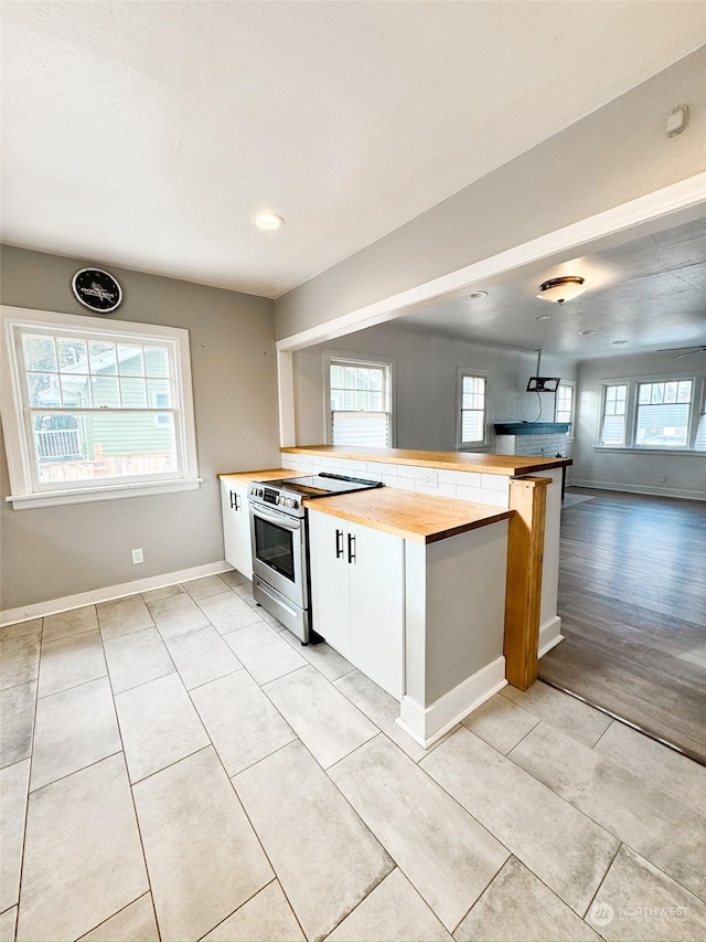 kitchen featuring plenty of natural light, wooden counters, electric range, and kitchen peninsula