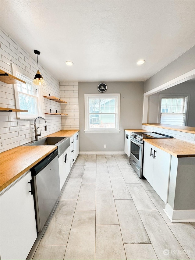 kitchen featuring appliances with stainless steel finishes, pendant lighting, tasteful backsplash, sink, and white cabinets