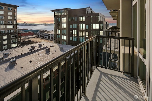 balcony at dusk featuring a water view