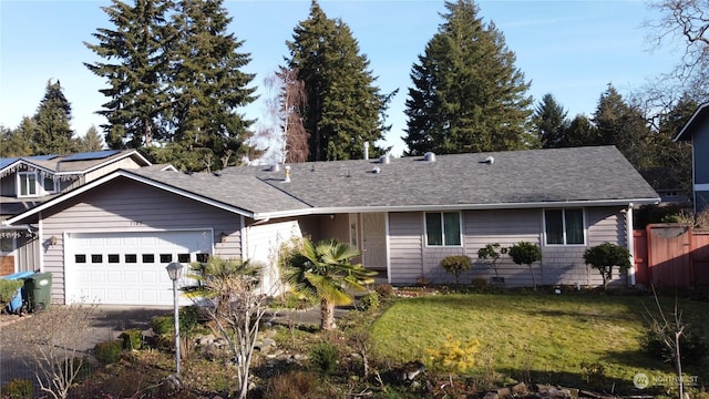 ranch-style house featuring an attached garage, driveway, roof with shingles, and a front yard