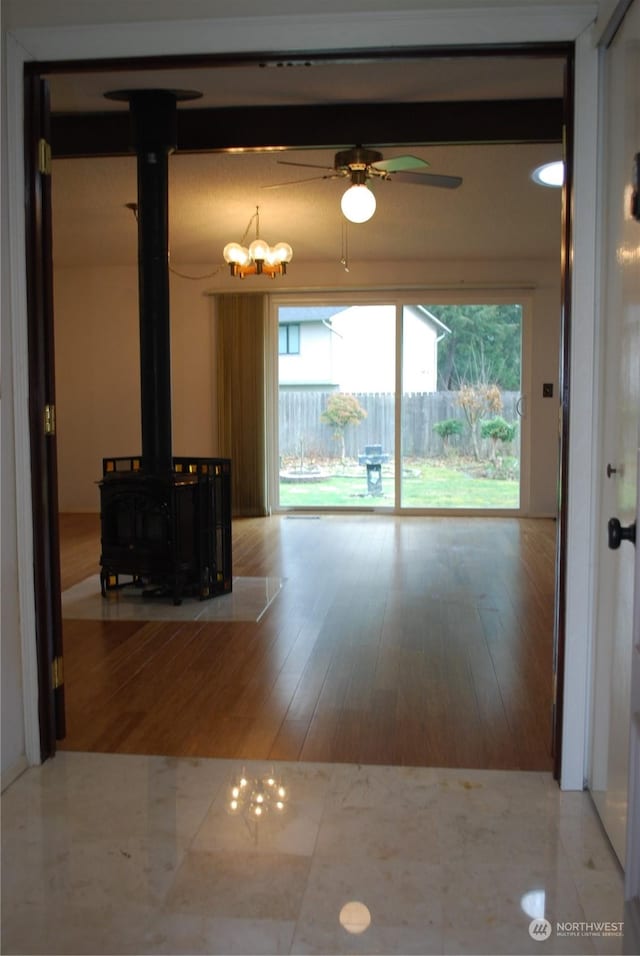 unfurnished living room with a wood stove, wood finished floors, and a ceiling fan