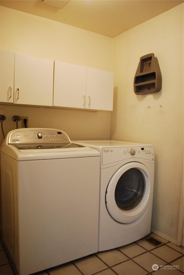 laundry room with cabinets, light tile patterned flooring, and washing machine and clothes dryer