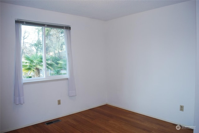 unfurnished room featuring dark wood-type flooring and a textured ceiling