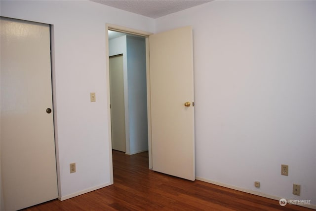 unfurnished bedroom featuring dark wood-type flooring and a textured ceiling