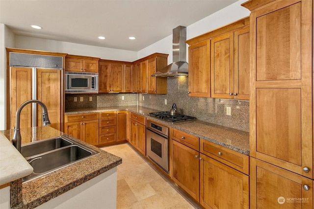 kitchen featuring built in appliances, decorative backsplash, wall chimney range hood, sink, and dark stone counters