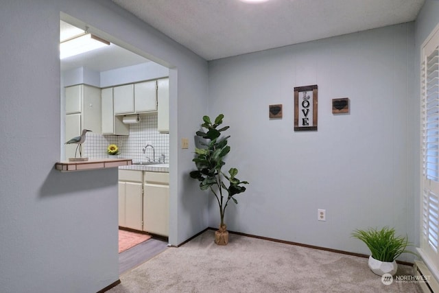 kitchen with light carpet, tile countertops, decorative backsplash, and sink