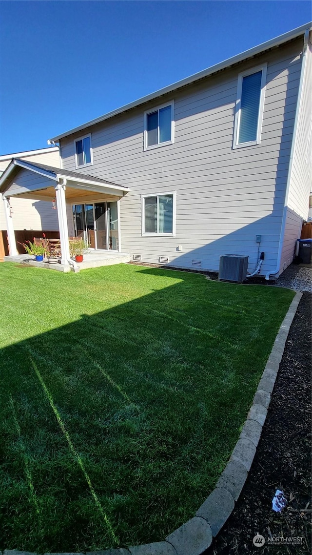 rear view of property featuring a patio, central AC unit, and a lawn