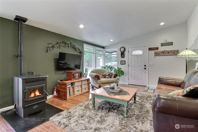 living room with lofted ceiling, a wood stove, and wood-type flooring