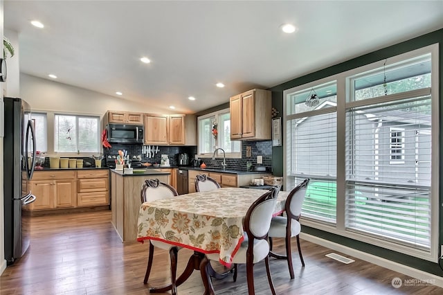 kitchen featuring wood-type flooring, vaulted ceiling, a wealth of natural light, refrigerator, and a center island