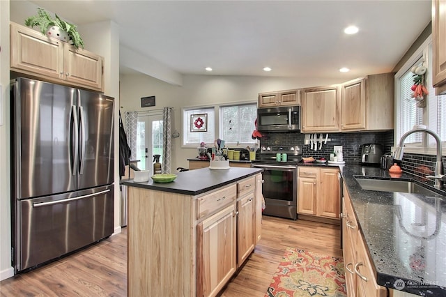 kitchen with tasteful backsplash, vaulted ceiling, a center island, sink, and appliances with stainless steel finishes