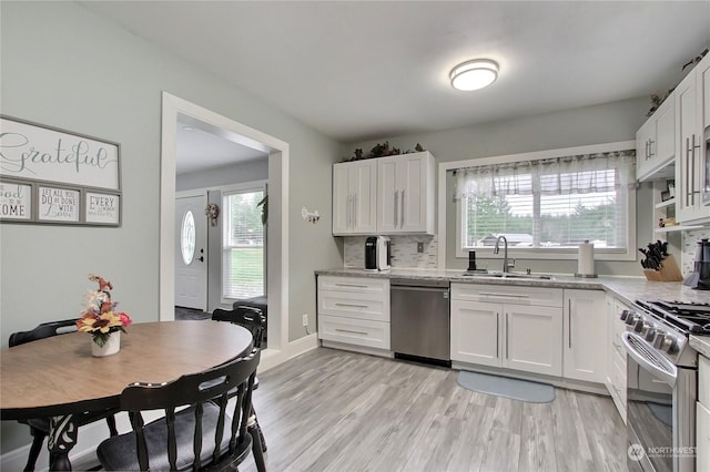 kitchen featuring white cabinets, appliances with stainless steel finishes, sink, and light stone counters