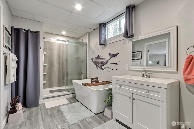 bathroom featuring hardwood / wood-style floors, vanity, a drop ceiling, and separate shower and tub